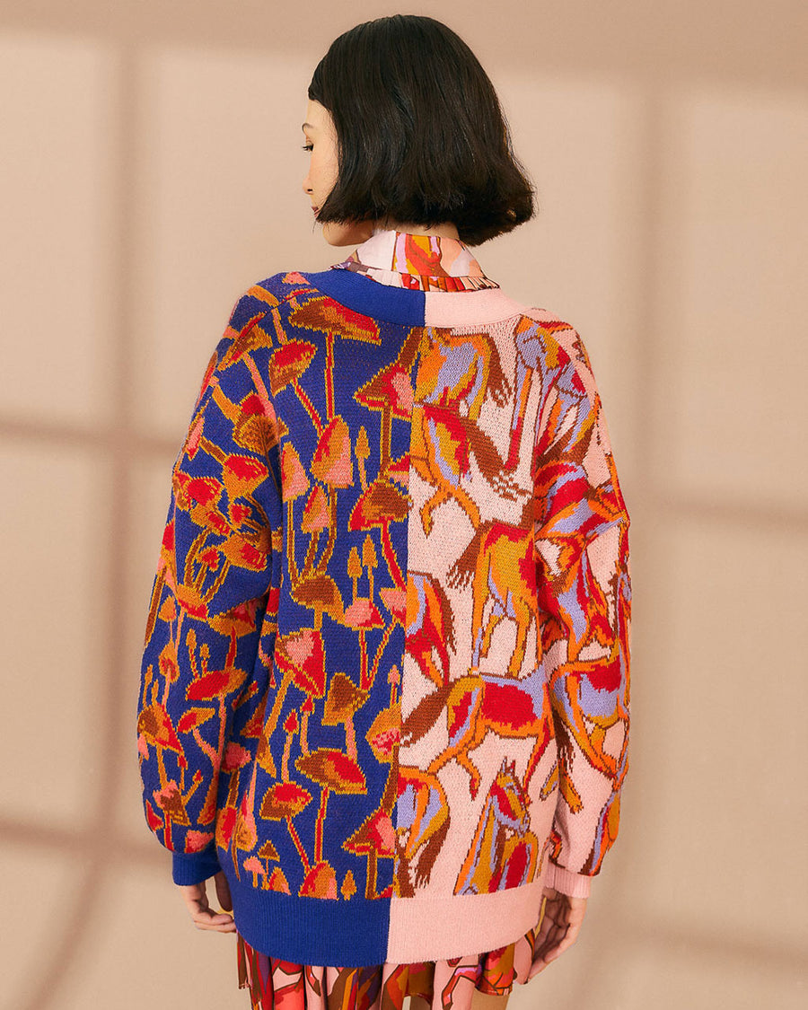 backview of model wearing cardigan with half blue mushroom print and half pink horse print