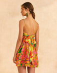back view of model wearing colorful painted birds print mini dress with ruffle detail on top and hem