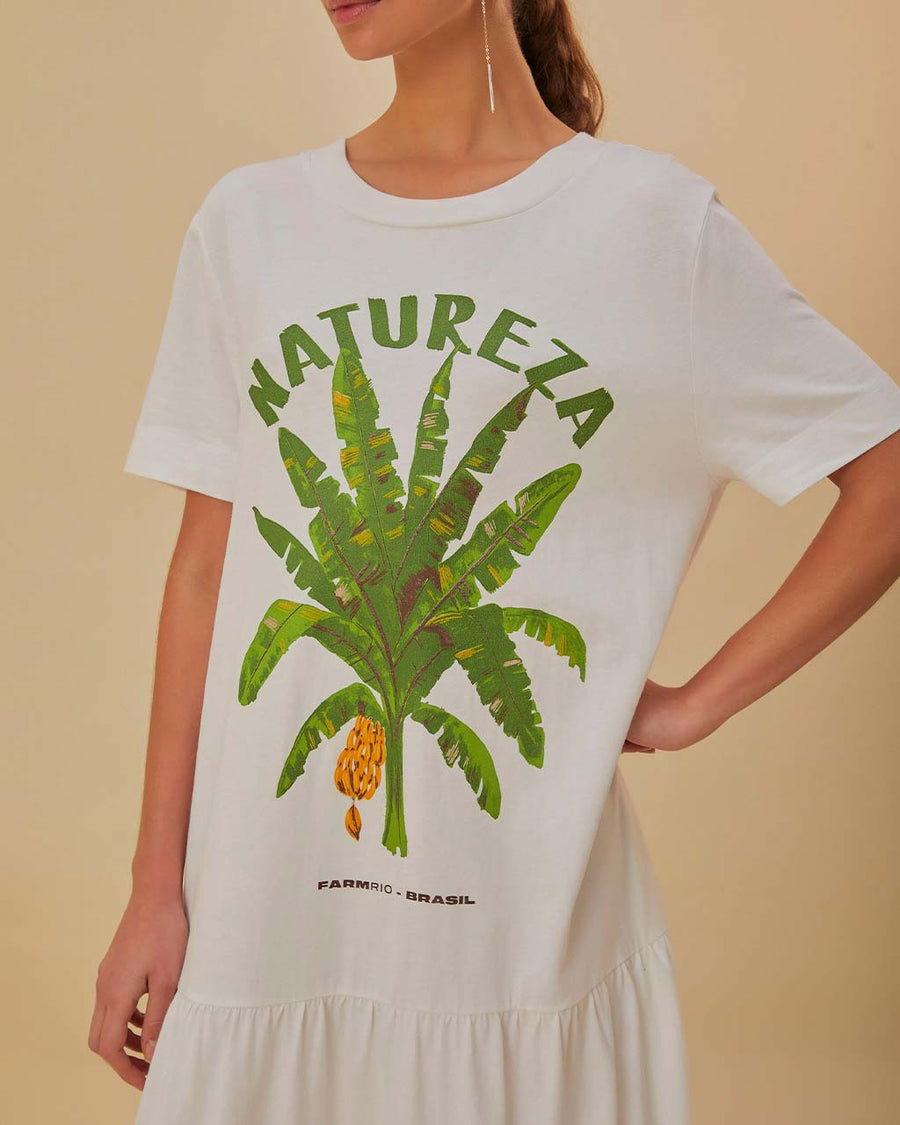 up close of model wearing white tee shirt maxi dress with 'natureze' and palm tree print, short sleeves and tiered skirt