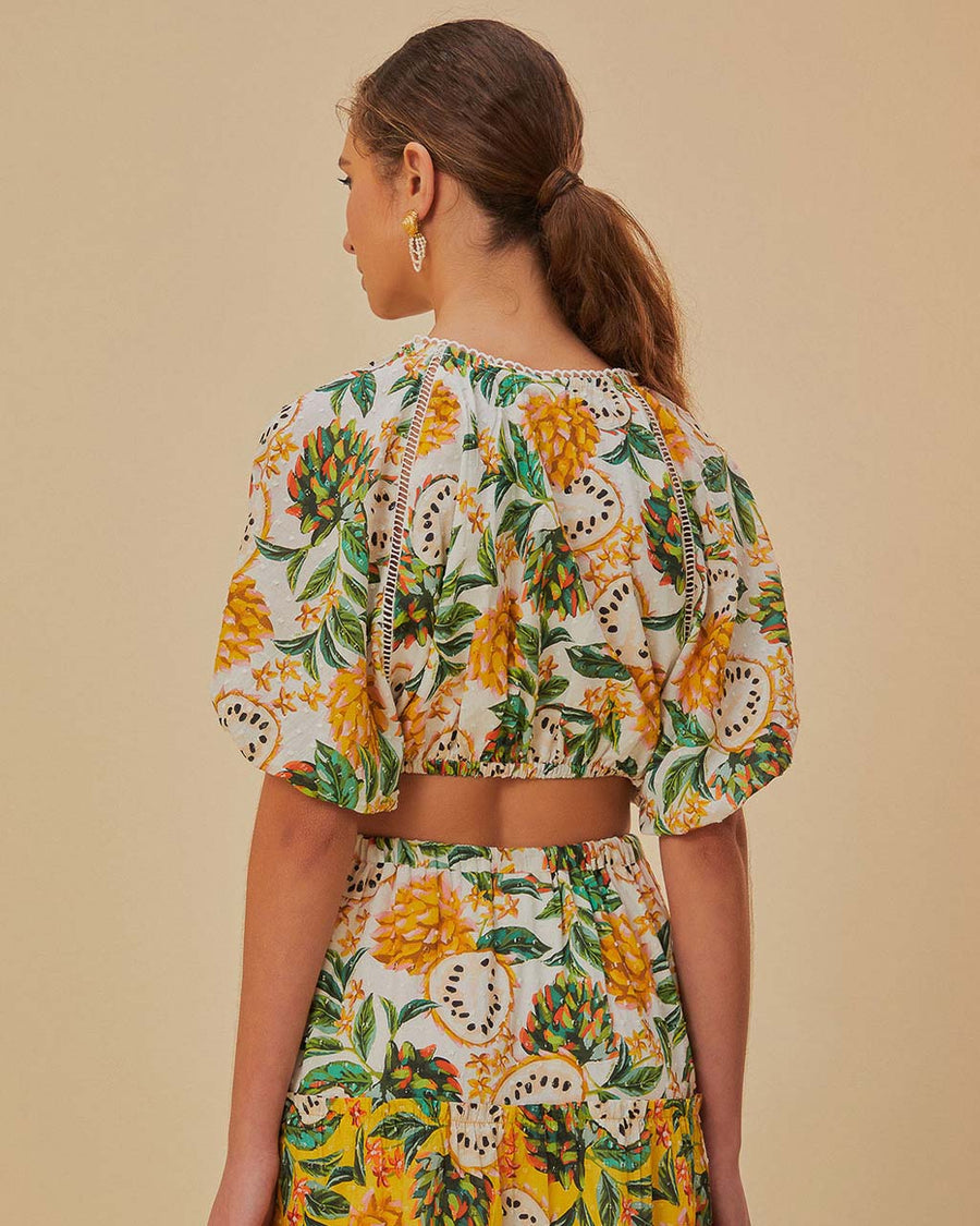 back view of model wearing white cropped blouse with mixed fruit print  and slight puff sleeves