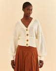 model wearing off white cropped cardigan with puff sleeves and large flower buttons