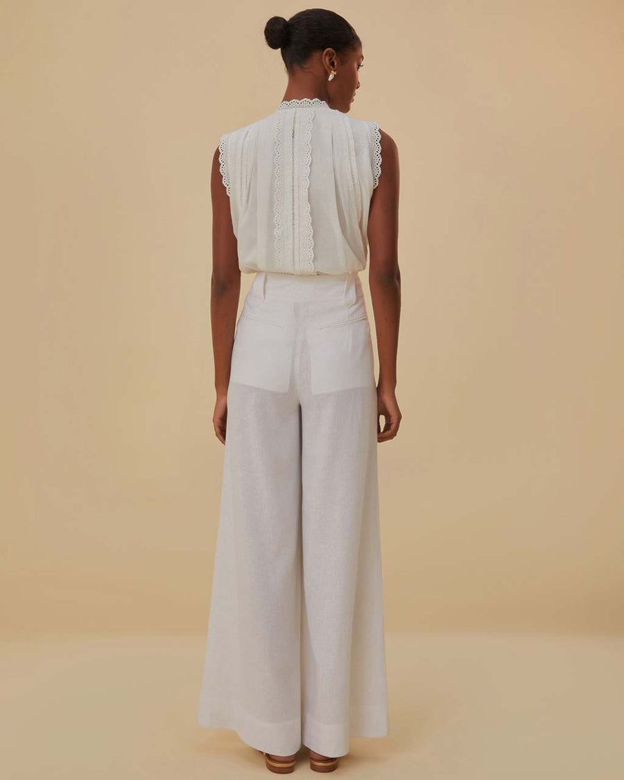 back view of model wearing white wide leg linen pants with gold belt detail