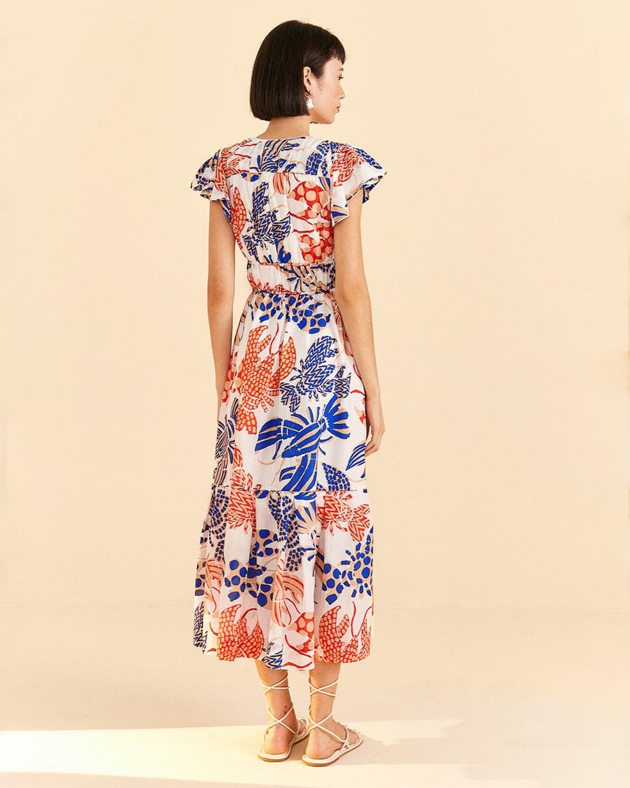 backview of model wearing white tiered midi dress with red and blue abstract lobster print, deep v, and tie waist
