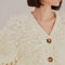 up close of model wearing textured off white slight cropped cardigan with with blouson sleeves 
