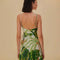 back view of model wearing white mini dress with side button detail, v-neckline and green tropical leaf print