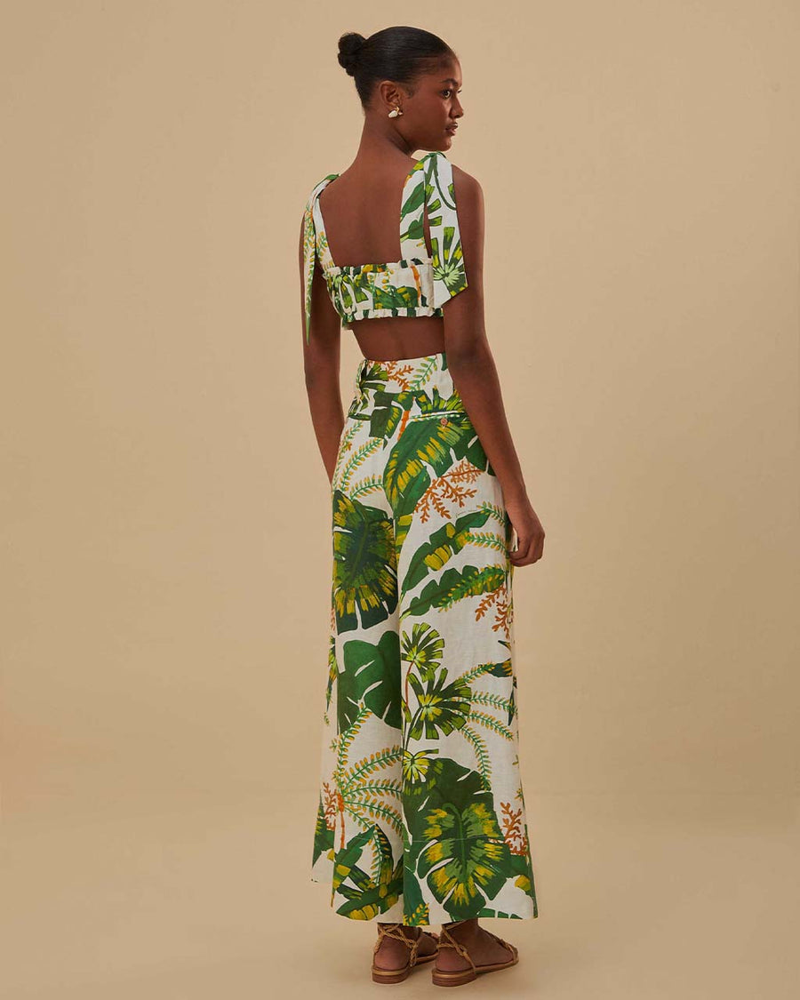 back view of model wearing white wide leg pants with green tropical print