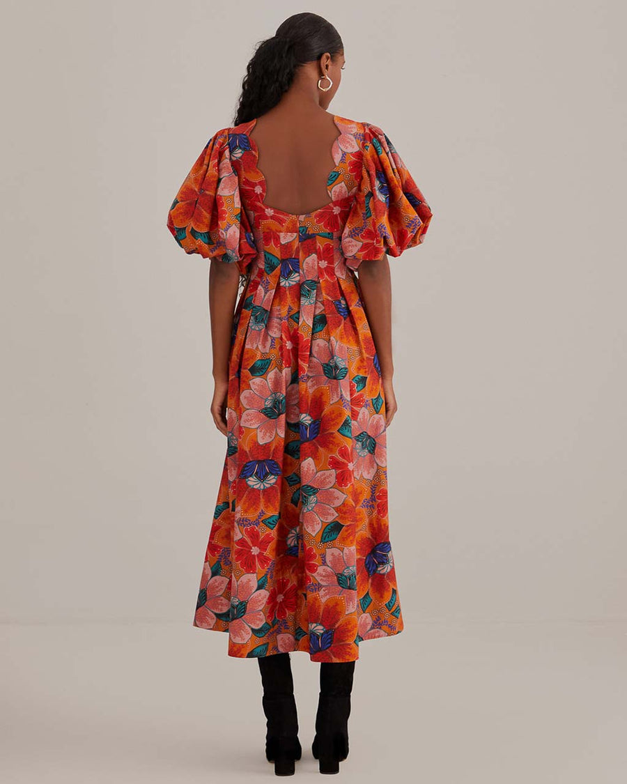 back view of model wearing orange abstract floral midi dress with cut-out front and puff sleeves