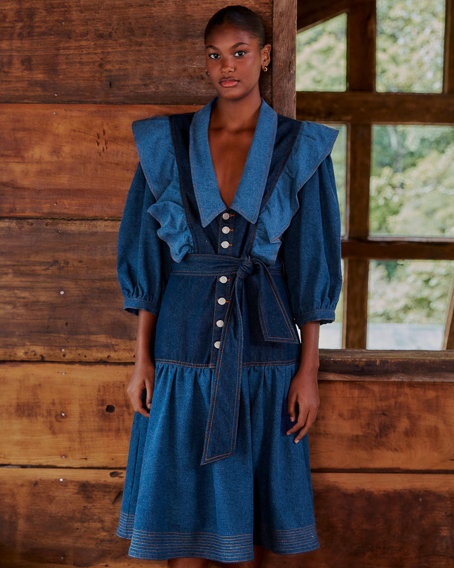 model wearing mixed denim midi dress with elongated collar, button front, ruffle shoulders and tie waist