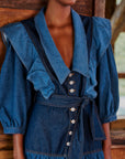up close of model wearing mixed denim midi dress with elongated collar, button front, ruffle shoulders and tie waist