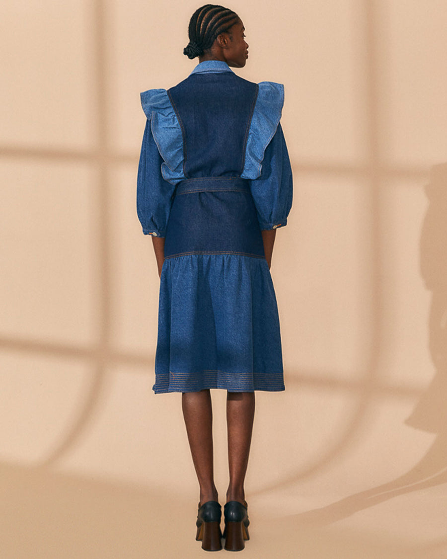 back view of model wearing mixed denim midi dress with elongated collar, button front, ruffle shoulders and tie waist