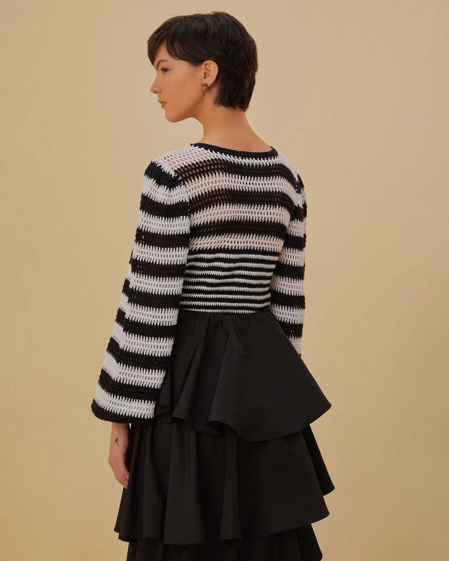 back view of model wearing black and white striped crochet top with long, flared sleeves