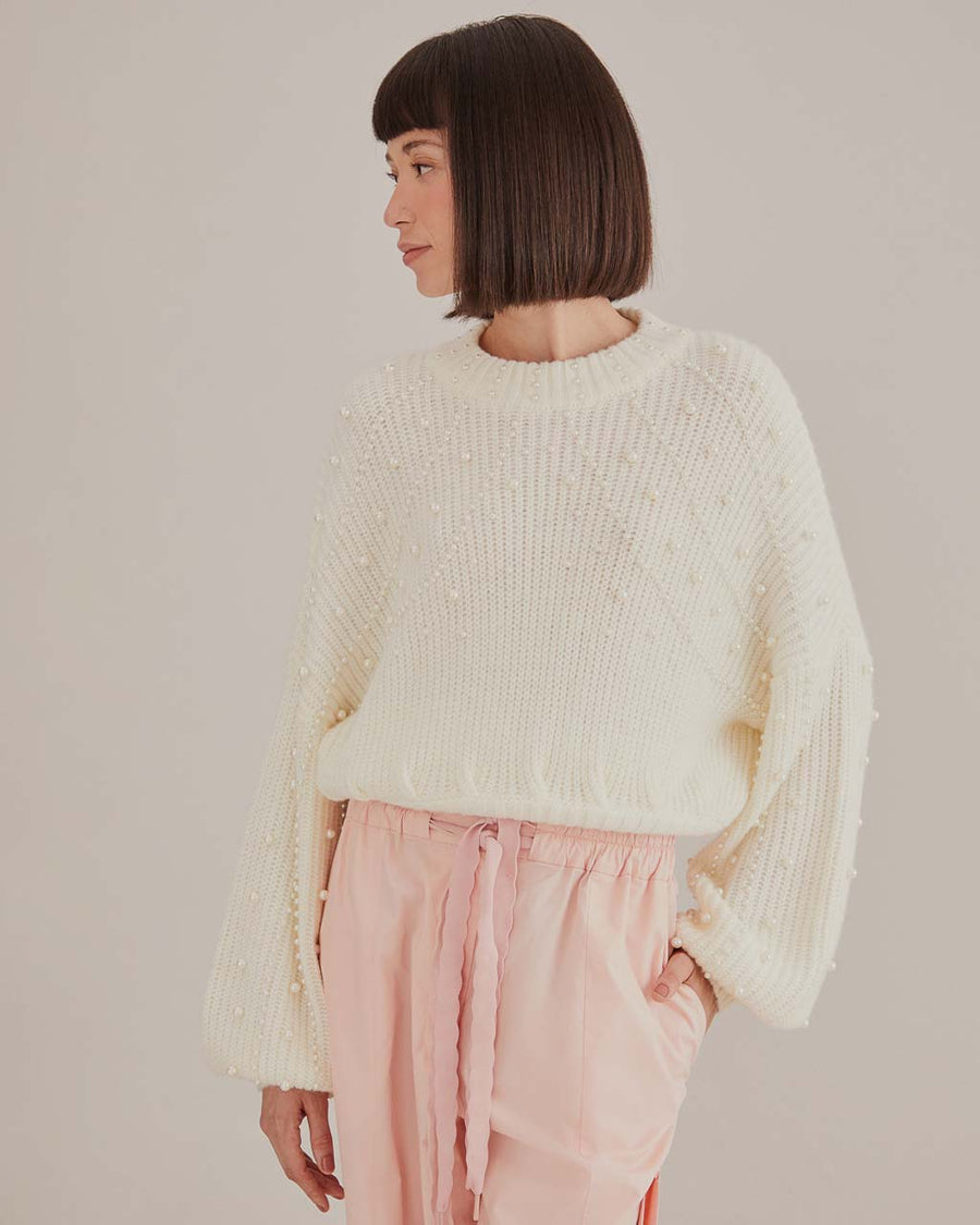 model wearing white sweater with puff sleeves and pearl detail