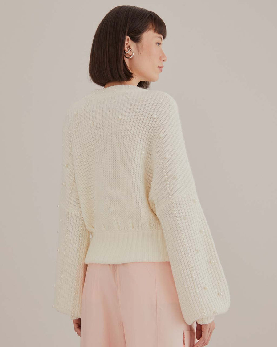 back view of model wearing white sweater with puff sleeves and pearl detail