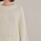 up close of model wearing white sweater with puff sleeves and pearl detail