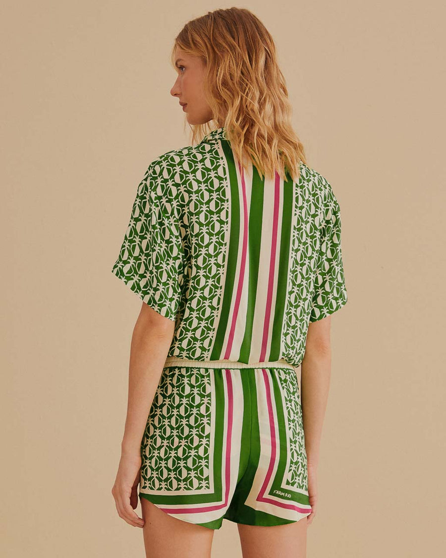 back view of model wearing green shorts with beaded tassel tie, pineapple print and red, white and green stripes down the front and back