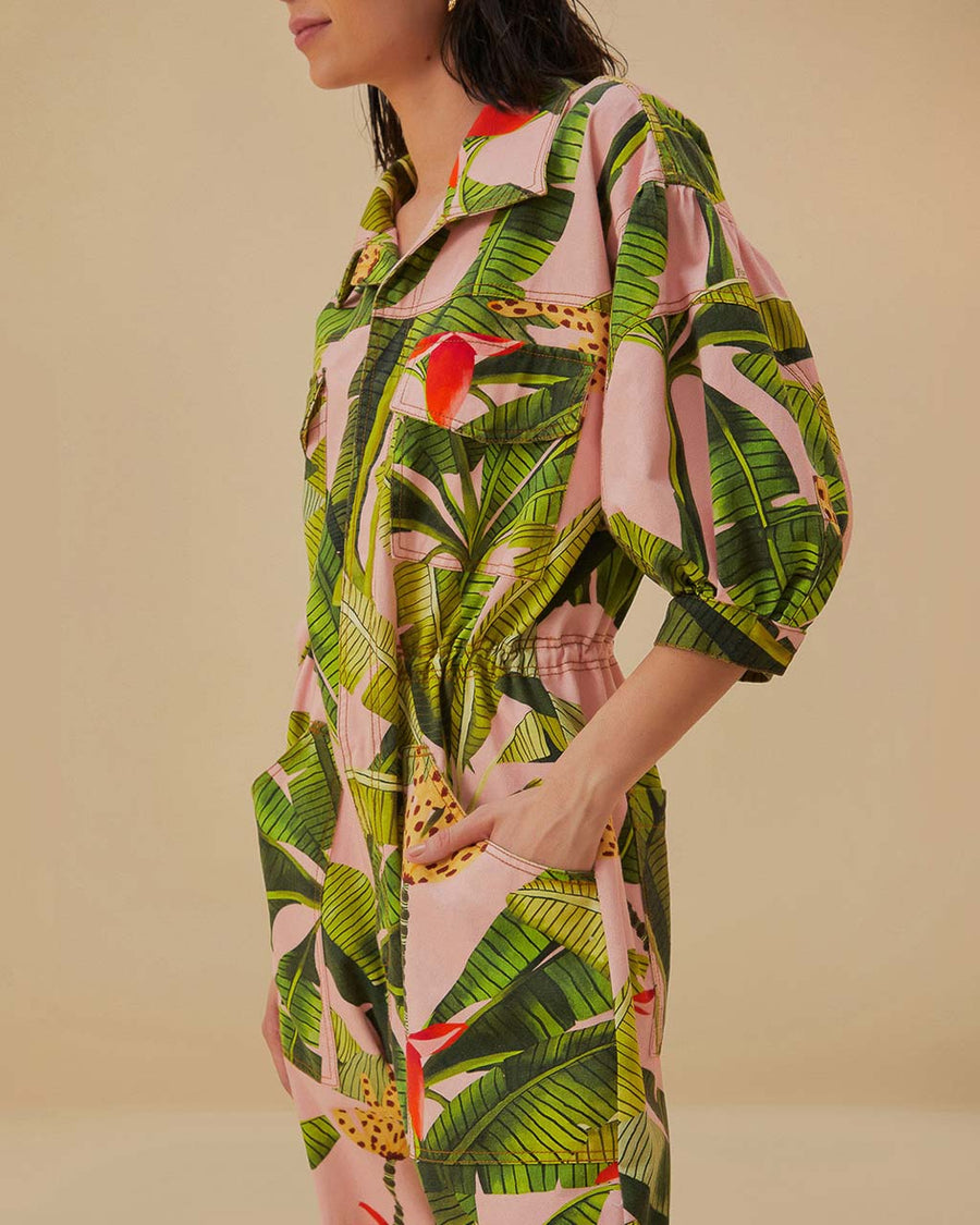 up close of model wearing pink jumpsuit with pockets, collar and all over banana leaves print