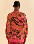 back view of model wearing pink cardigan with croc print and large tortoise buttons