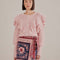model wearing pink chunky knit cardigan with ruffle shoulders