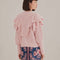 back view of model wearing pink chunky knit cardigan with ruffle shoulders