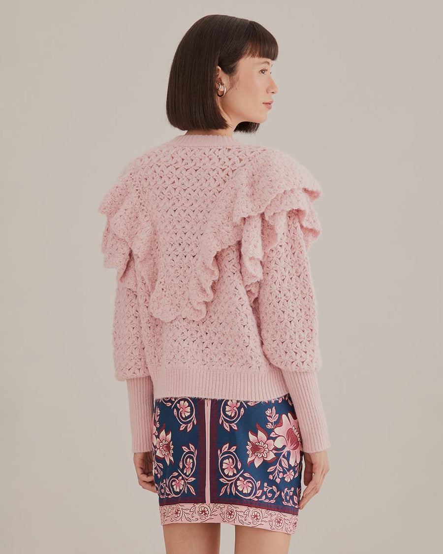back view of model wearing pink chunky knit cardigan with ruffle shoulders