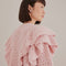up close of model wearing pink chunky knit cardigan with ruffle shoulders