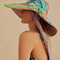 side view of model wearing wide brim sun hat with colorful abstract print and pink floral print