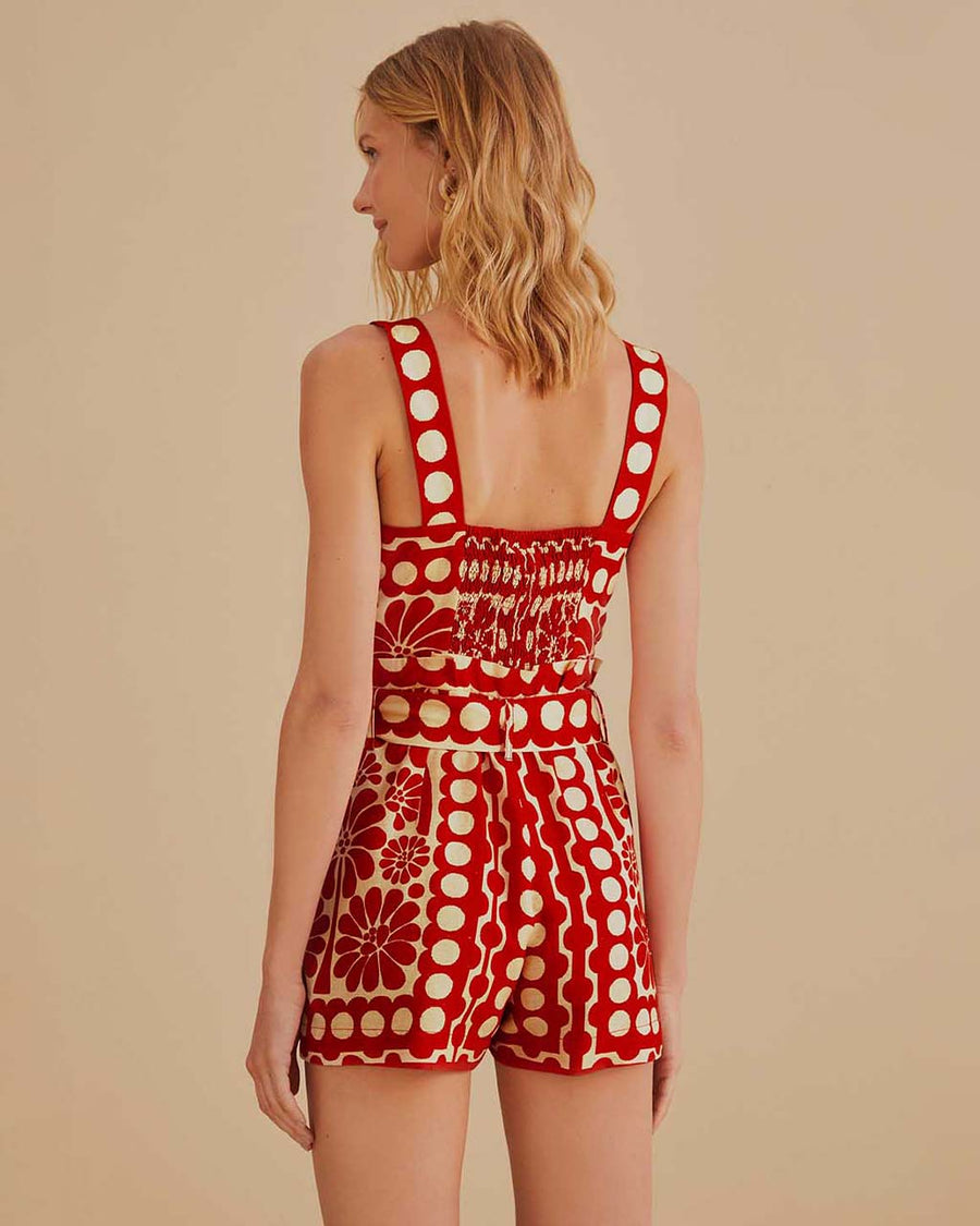 back view of model wearing cream and red abstract romper with tie waist and button front