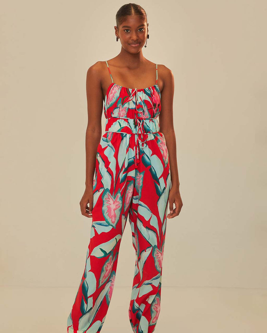 model wearing red tank jumpsuit with green leaf print and cuffed leg openings