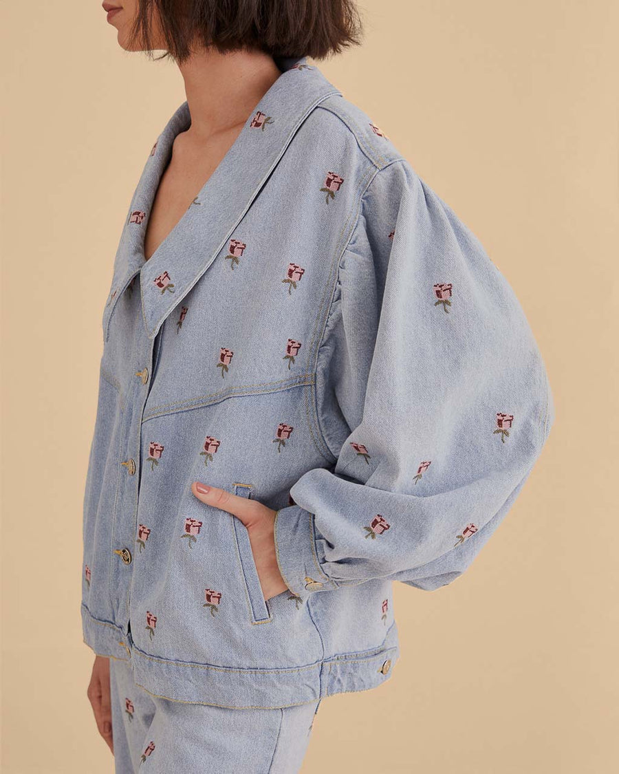 side view of model wearing light denim jacket with oversized collars and pink embroidered floral print