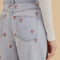 up close of model wearing wide leg light denim with embroidered pink flowers