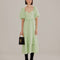 model wearing soft green midi dress with ruffle hem and waist, puff sleeves and stitched corset bodice