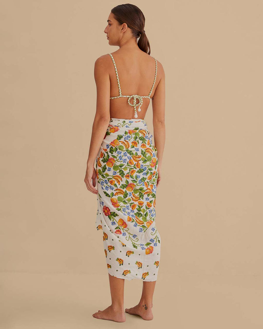 back view of model wearing white sarong with colorful embroidered floral and banana print