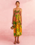 model wearing pink and orange ombre midi dress with vibrant tropical print and rope like belt and straps