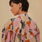 up close of model wearing colorful abstract print with puff short sleeves, button front and ruffle across the bodice