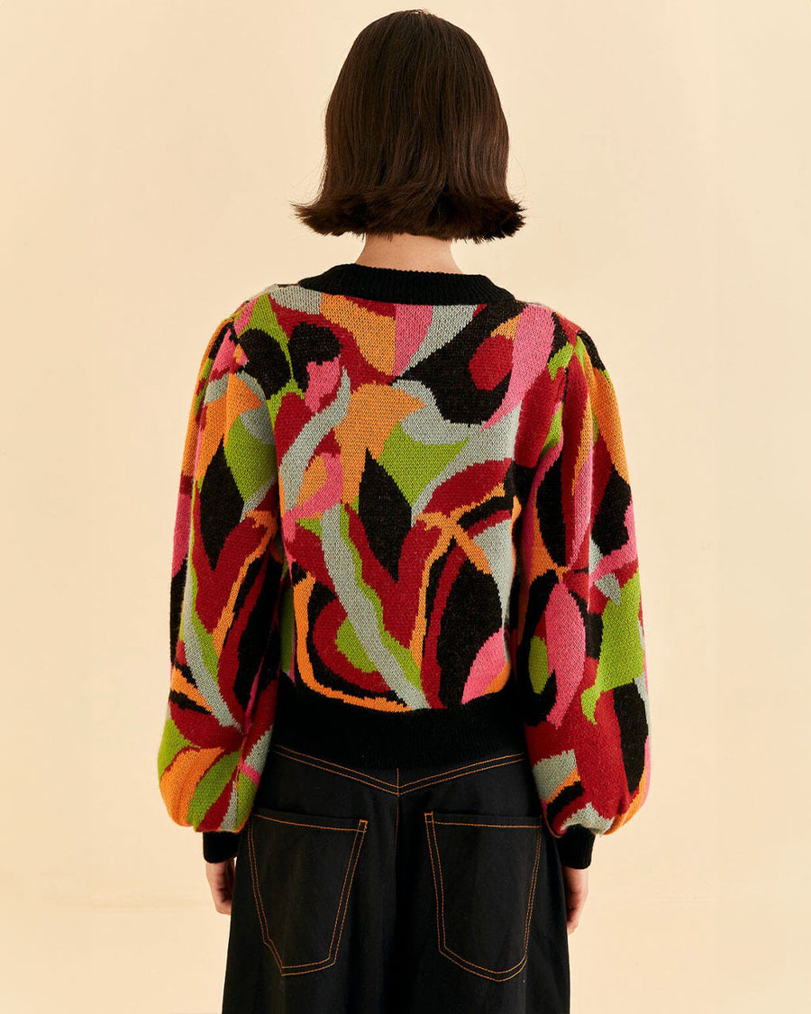 back view of model wearing colorful sweater with black neckline, cuffs and waistband