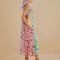 side view of model wearing colorful floral patchwork midi dress with pom seam detail and pockets