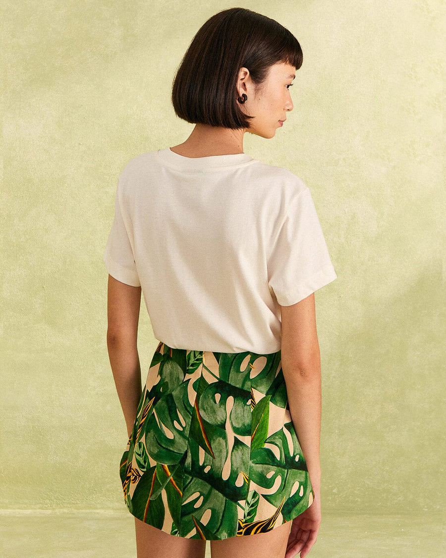 back view of model wearing nude shorts with tropical leaf print, bamboo belt, and white pepper tee