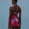 back view of model wearing pink, red, and blue floral print shorts with tie waist and beaded tassels