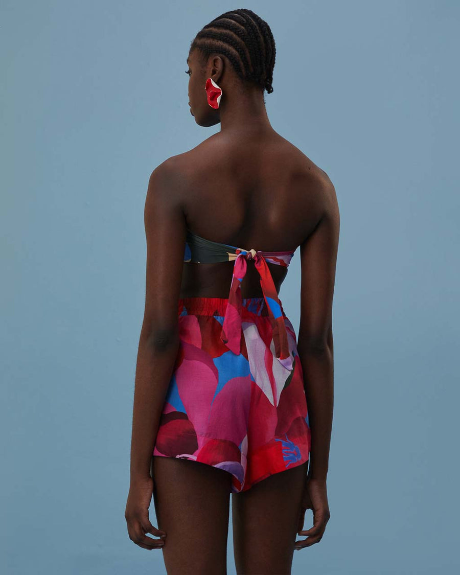back view of model wearing pink, red, and blue floral print shorts with tie waist and beaded tassels