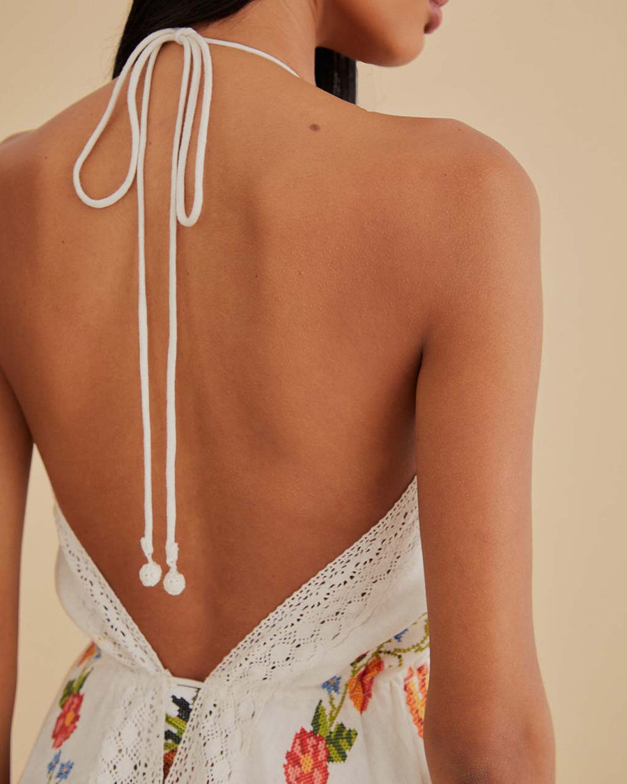 up close of model wearing white lace cover up with colorful cross-stitch, tie front and halter strap