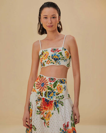 model wearing white cropped top with eyelet and colorful floral detail