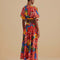 back view of model wearing blue cotton midi skirt with yellow, red and orange cold floral print, side pockets and tie waist and matching cropped top