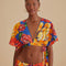 model wearing blue cropped v-neck top with bold yellow, pink and red floral print