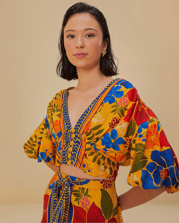 model wearing yellow cropped top with bold colorful floral print and puff sleeves