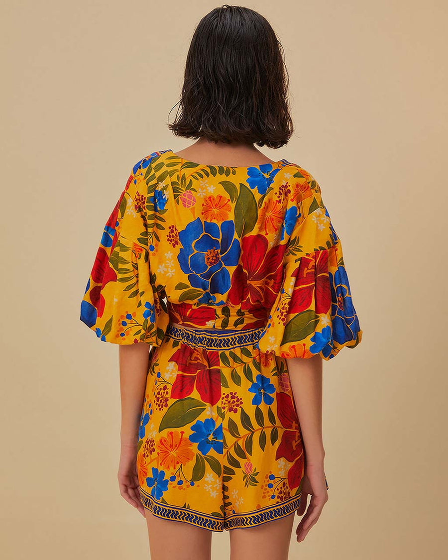 back view of model wearing yellow cropped top with bold colorful floral print and puff sleeves