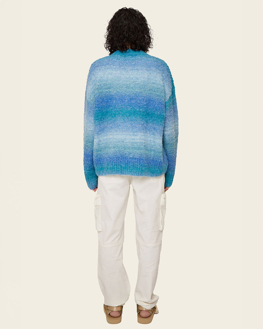 back view of model wearing blue gradient oversized cardigan with patch pockets and brown button front