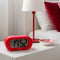 red digital alarm clock with pink trim on a bedside table