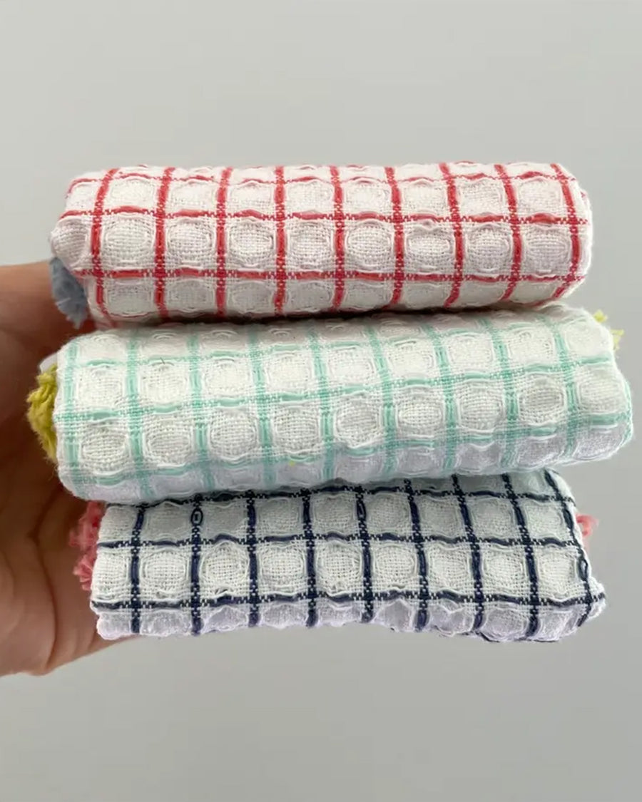 folded set of three plaid dishcloths with fringe: red with blue fringe, mint with yellow fringe, and navy with rose fringe