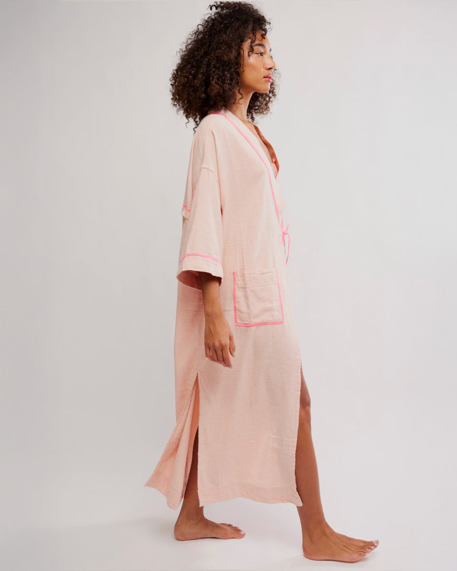 sideview of model wearing pink long robe with bright pink trim