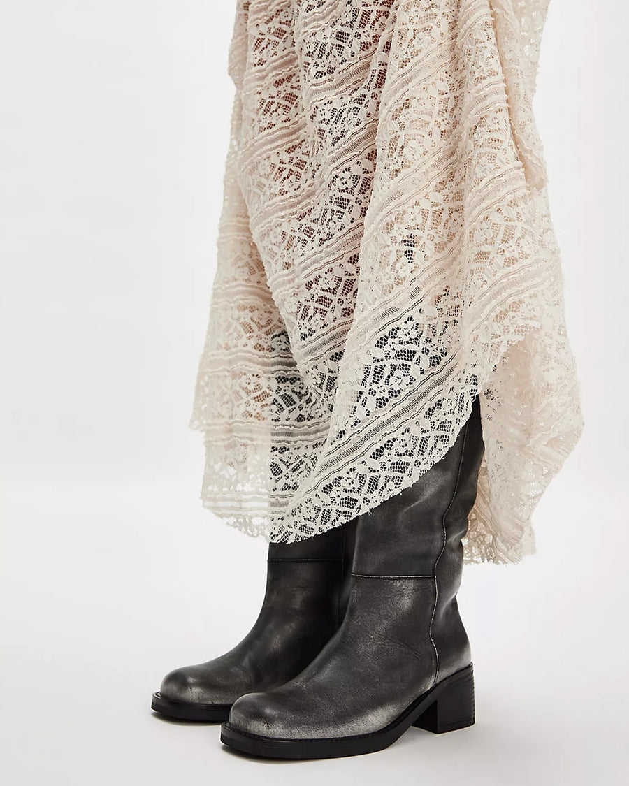 side view of model wearing black distressed leather pull-on tall boots